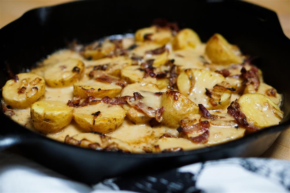 Potatoes and bacon with cheese sauce in cast iron skillet